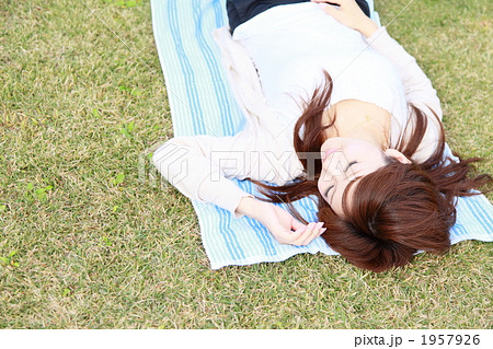 仰向け 若い女性 笑み 寝そべるの写真素材