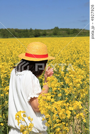 女の子 後姿 菜の花 麦わら帽子の写真素材