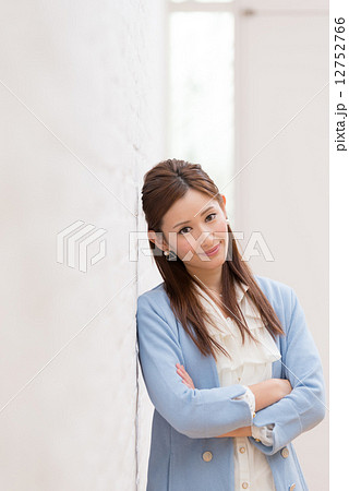 腕組み 寄りかかる 女性 壁の写真素材