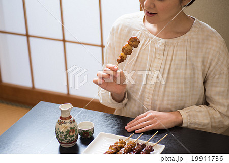 日本酒 食べる 女性 焼き鳥の写真素材