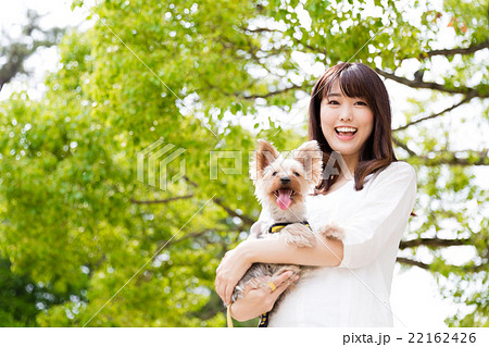 女性 犬 抱く 笑顔の写真素材