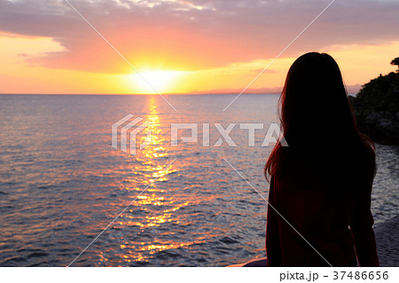 後ろ姿 女性 夕日 海の写真素材