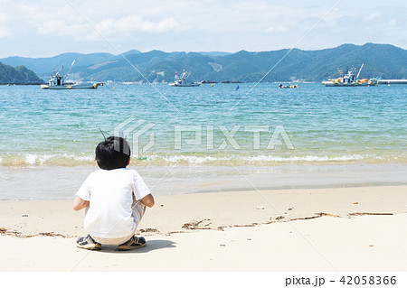 男の子 後姿 しゃがむ 水平線の写真素材