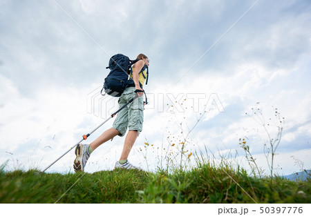 Sporty Woman Hiker with Backpack and Trekking Sticks Hiking in the