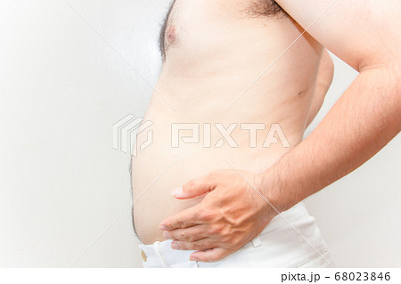 中年太りの男性の上半身 下腹を抱える毛深い男性の写真素材