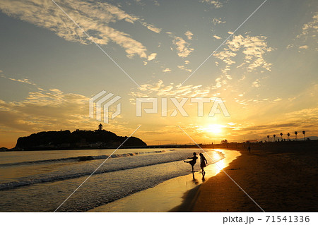 海 夕焼け 女の子 波打ち際の写真素材