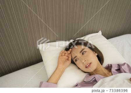 病気で寝込んでいる女性/体調の悪い女性/ベットに寝ている美しい女性