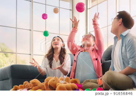 Happy asian family sitting on carpet and playing throw a lot of colored balls with their daughter down syndrome child, Activity happy family lifestyle concept.