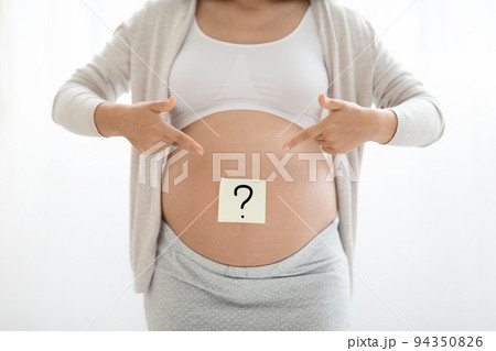 A Pregnant Woman Topless in Pajama Pants in Profile in a Home