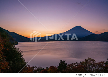 The boy is sitting on a folding chair on the shore of a lake or