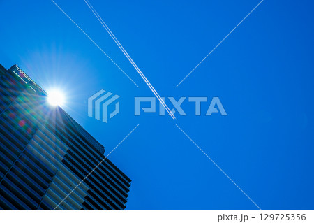 高層マンションの上空を飛ぶ旅客機とひこうき雲